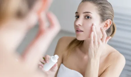 Woman applying cream on her face in a bathroom